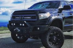 the black truck is parked on the side of the road with mountains in the background