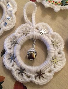 three white crocheted ornaments with bells and snowflakes hanging on the wall