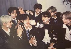 group of young men posing together in front of a wall with their hands up to the camera