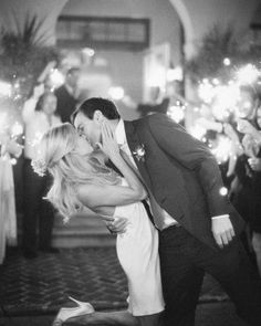 a couple kissing each other in front of a cake with candles and flowers on it