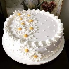 a white cake decorated with daisies on a table