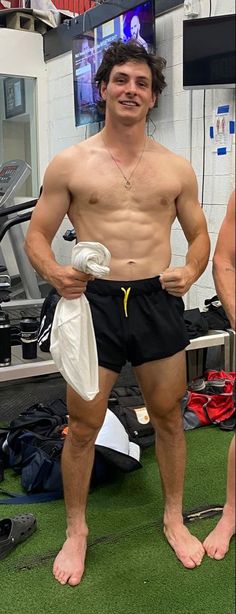 a man with no shirt standing in a gym