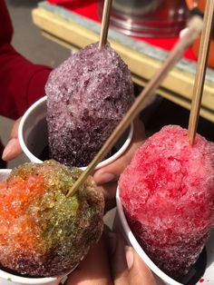 three bowls filled with different colored ice creams and chop sticks sticking out of them