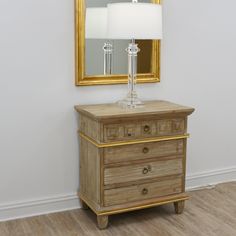 a wooden dresser sitting next to a mirror and lamp on top of a hard wood floor