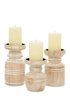 three white candles are sitting in wooden containers