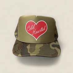 Looking for a stylish and cool trucker hat to complete your casual look? Look no further than the Cold Hearted Trucker Hat! This trendy foam mesh trucker hat comes in a cool camo, and features a bold red heart design on the front that is sure to turn heads. Whether you're hanging out on the beach, running errands around town, or just lounging at home, this hat is the perfect accessory to add some flair to your outfit. The adjustable snapback closure ensures a comfortable fit for all head sizes, Winter Trucker Hat With Curved Brim, Trendy Winter Trucker Hat, Trendy Winter Trucker Hat Snapback, Trendy Winter Trucker Snapback Hat, Red Heart Design, Camo Trucker Hat, Beach Running, Custom Trucker Hats, Cold Hearted