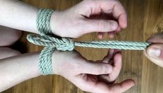 two hands holding a rope on top of a wooden floor