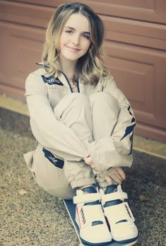 a young woman sitting on top of a skateboard in front of a garage door