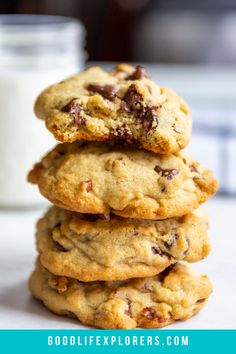 chocolate chip cookies stacked on top of each other with a glass of milk in the background