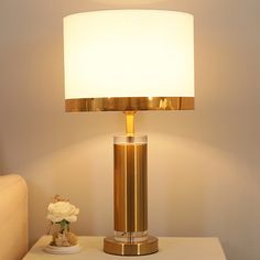 a table lamp sitting on top of a white table next to a couch and chair