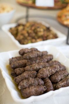 there are many different types of food in the dishes on the buffet table, including meatballs and pizzas