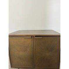 a brown cabinet with two doors and wheels on the bottom, in front of a white wall