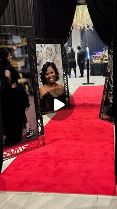 a red carpeted area with black curtains and pictures on the wall, in front of people