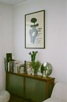 a living room with a book shelf, chair and art on the wall above it