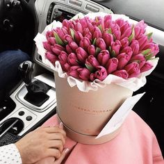 a person sitting in a car with a bouquet of flowers on their head and the steering wheel behind them