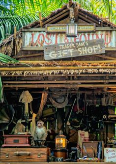 the front of a store with lots of items on display and palm trees in the background