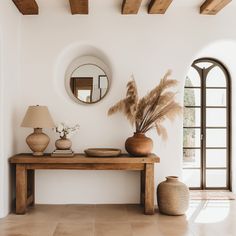 a table with vases and mirrors on it in front of an arched doorway that leads to another room