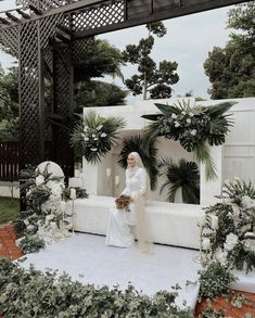 a woman in white is sitting on a stone bench surrounded by greenery and flowers