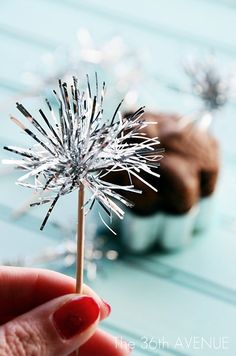 a hand holding a small silver flower on top of a table