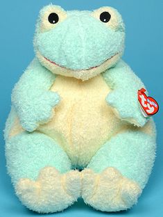 a stuffed frog sits on a blue background