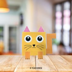 a paper cat sitting on top of a wooden table