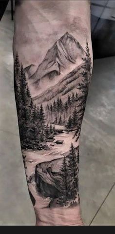 a man's arm with an image of mountains and trees on the inside of it