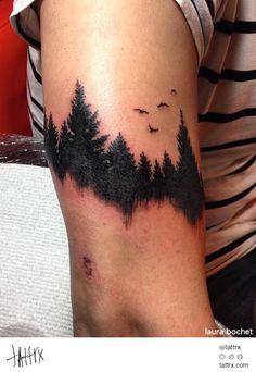 a person with a tattoo on their arm that has trees and birds in the sky