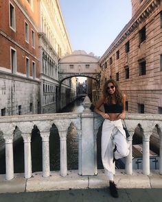 a woman leaning on a wall next to a canal