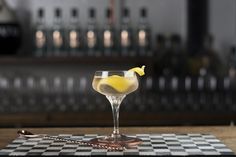 a glass filled with yellow liquid sitting on top of a checkered table