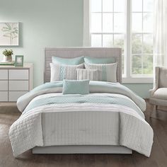 a bed with blue and white comforters in a bedroom next to a window,