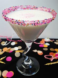 a martini glass filled with white liquid and sprinkles