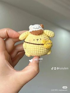 a hand holding a small crocheted toy with a sheep on it's head