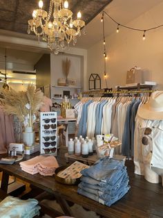 a clothing store with clothes and hats on display in front of a chandelier