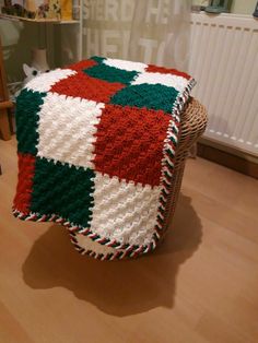 a crocheted blanket sitting on top of a wicker chair next to a radiator