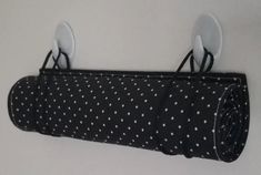 three white spoons are hanging on a black polka dot fabric roll with two forks