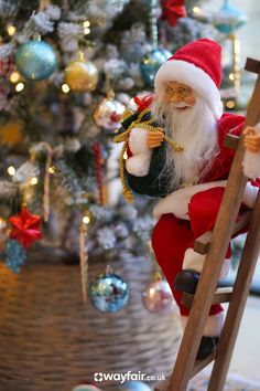 a santa clause figurine sitting on top of a ladder next to a christmas tree