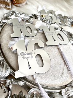 the table numbers are silver and have white letters on them with tassels attached to them