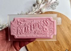 a pink soap bar sitting on top of a wooden cutting board next to a christmas tree