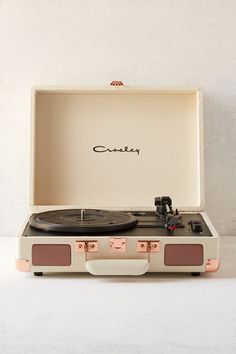 an old record player sitting in a case on top of a white surface with the word crosley written above it