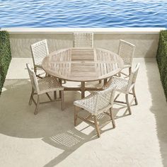 an outdoor table and chairs on a balcony overlooking the water with grass growing around it