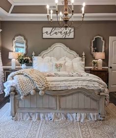 a white bed sitting under a chandelier in a bedroom