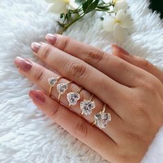 a woman's hand with three different rings on her fingers and one is holding a flower