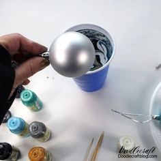 a person is holding an ornament in front of some crafting supplies on a table