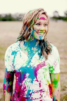 a woman with paint all over her face standing in the middle of an open field