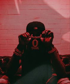 a person sitting on a couch with their hands in front of his face, holding a chain