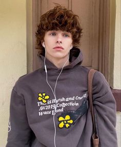 a young man with headphones standing in front of a door wearing a sweatshirt that says, this is harsh and cruel