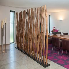 a room divider made out of wood sticks in front of a table and chairs