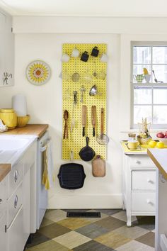 a kitchen with yellow pegboard and utensils hanging on the wall