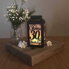 a wooden table topped with a vase filled with white flowers and a lit up candle