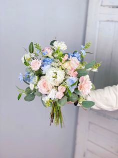 a person holding a bouquet of flowers in their hand with white and pink blooms on it